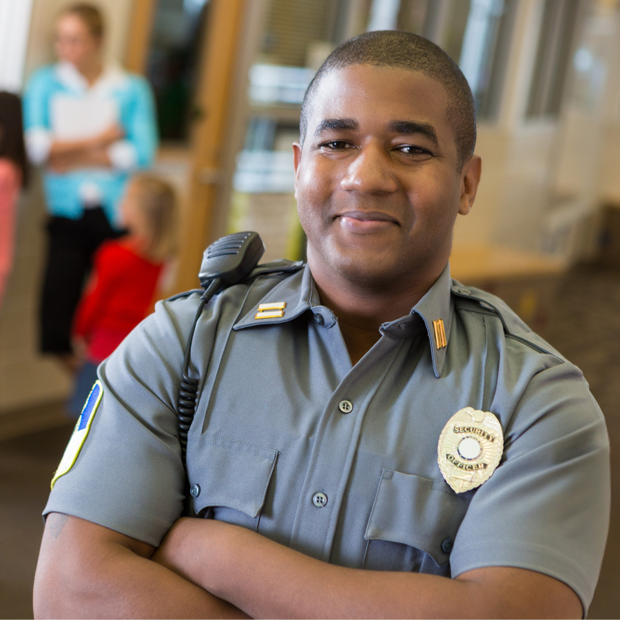PIcture of a smiling school security guard with blurred kids in background